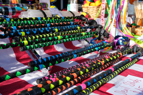 A stack of brightly coloured devil sticks sits at a market stall