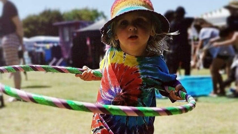 A little girl plays with a hula hoop at a fair