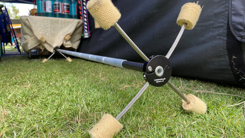 An unlit fire dragon staff sits on the grass with a market stall in the background