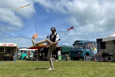 A person flicks a fire spin staff under their legs at a fair