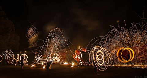 A group of fire spinners performs in a park at night