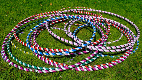 A stack of brightly coloured hula hoops sits on vivid green grass