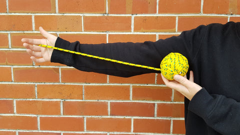 A person holds up a poi against their arm to show how long a poi should be