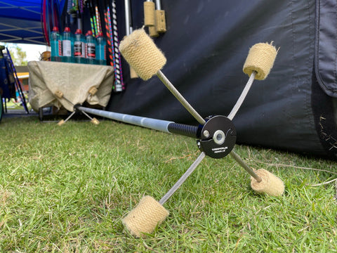 A fire dragon staff sits on the grass with a market stall in the background