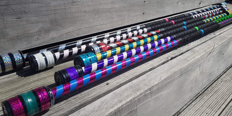 Six brightly coloured spin staff of varying sizes sit on a wooden step