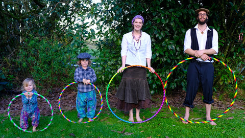A family stands in nature holding various sizes of hula hoops in front of them