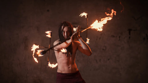 A person rolls a lit fire dragon staff on his arms