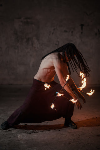 A man leans forward with a fire dragon staff rolling between his arms and legs