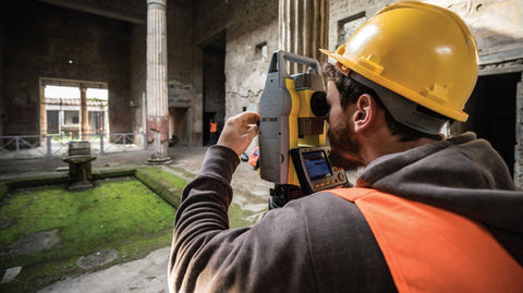 Surveyor using a total station for archaeology