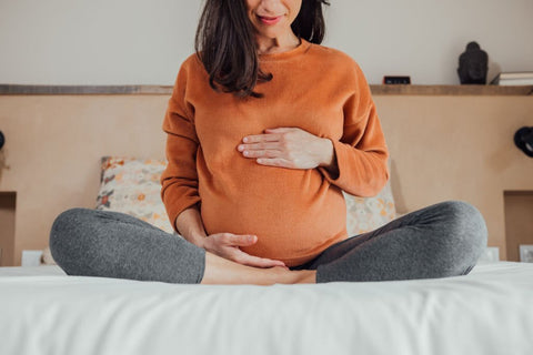 a pregnant woman sitting on the bed