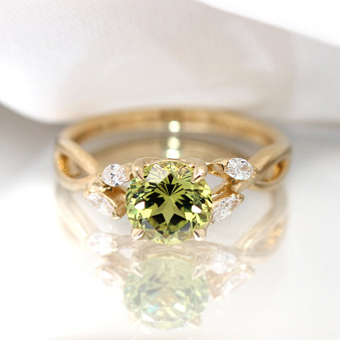 green sapphire engagement ring with diamond details on the band set in 18k gold