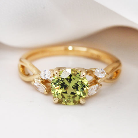green sapphire engagement ring with diamond details on the band set in 18k gold