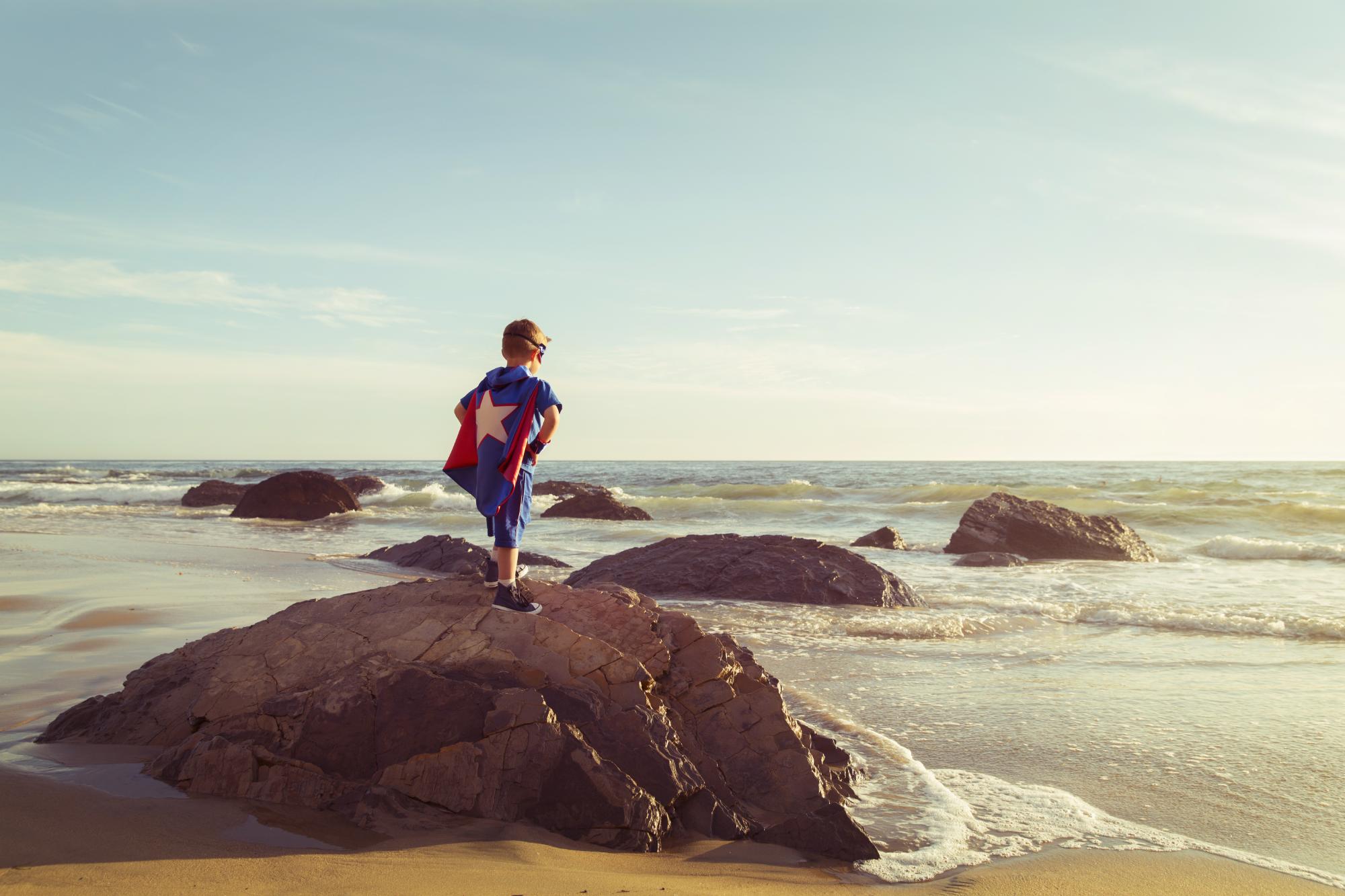 Boy Dressed as Superhero stands on California Beach