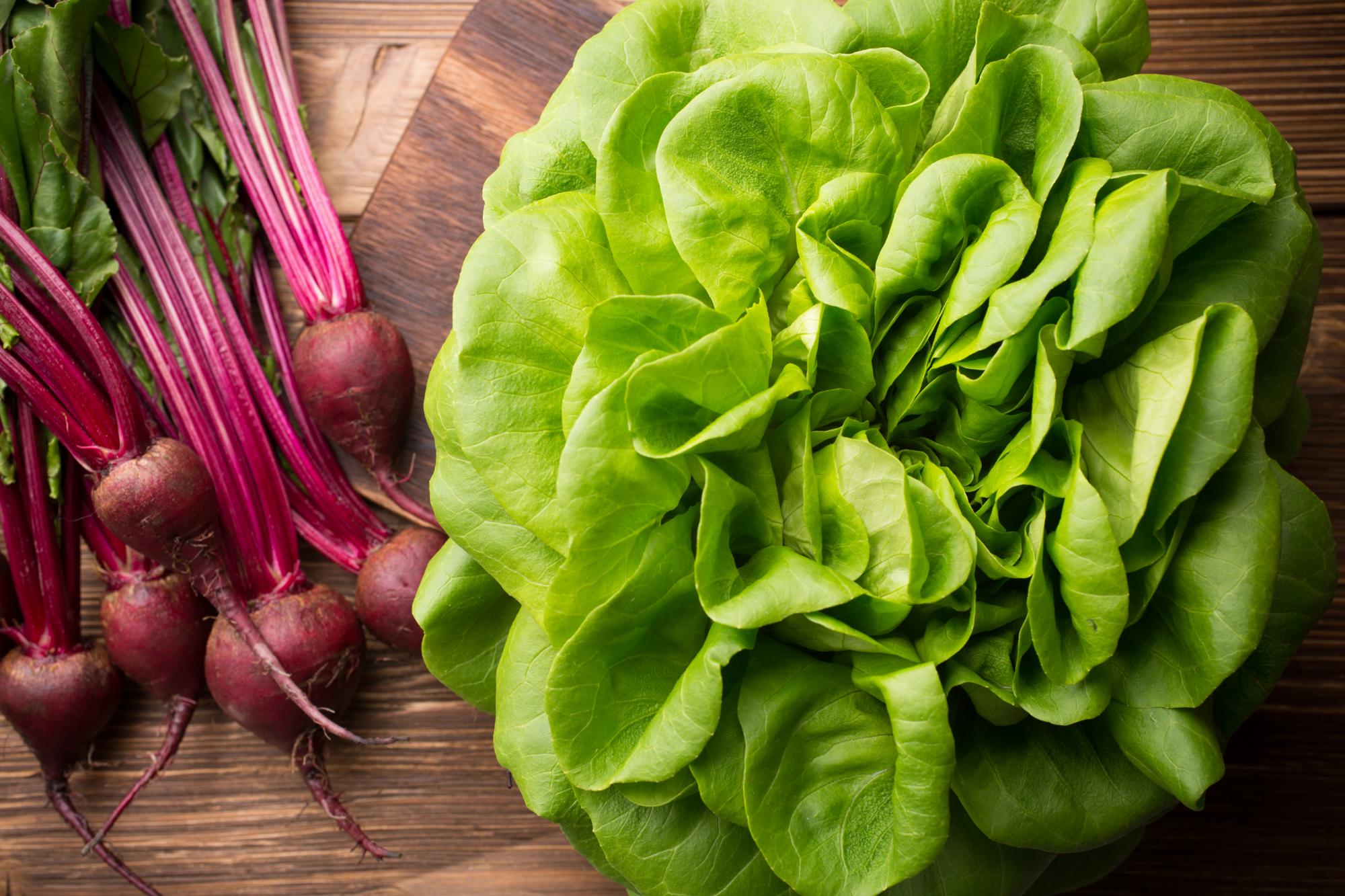 Vegetables, salads, beetroot, spinach. On a wooden background.