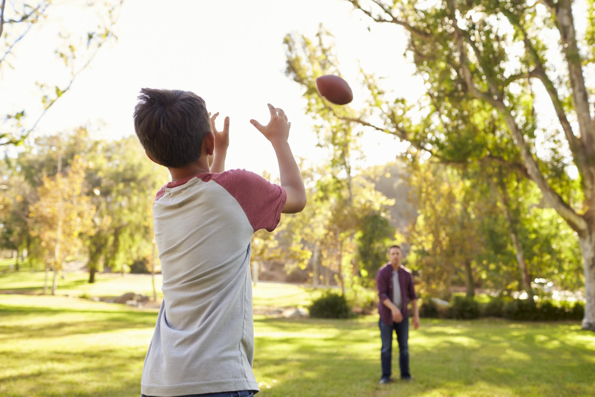 Dad and son throwing football to each other