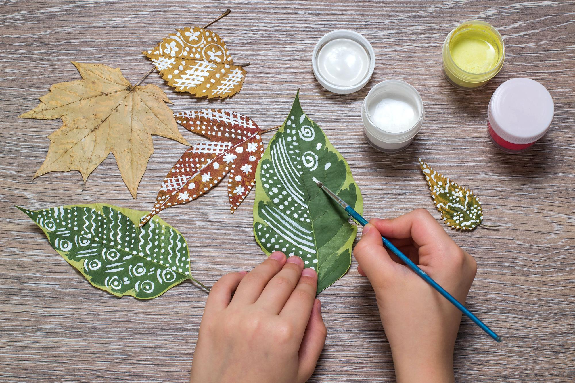Girl paints patterns of dry autumn leaves