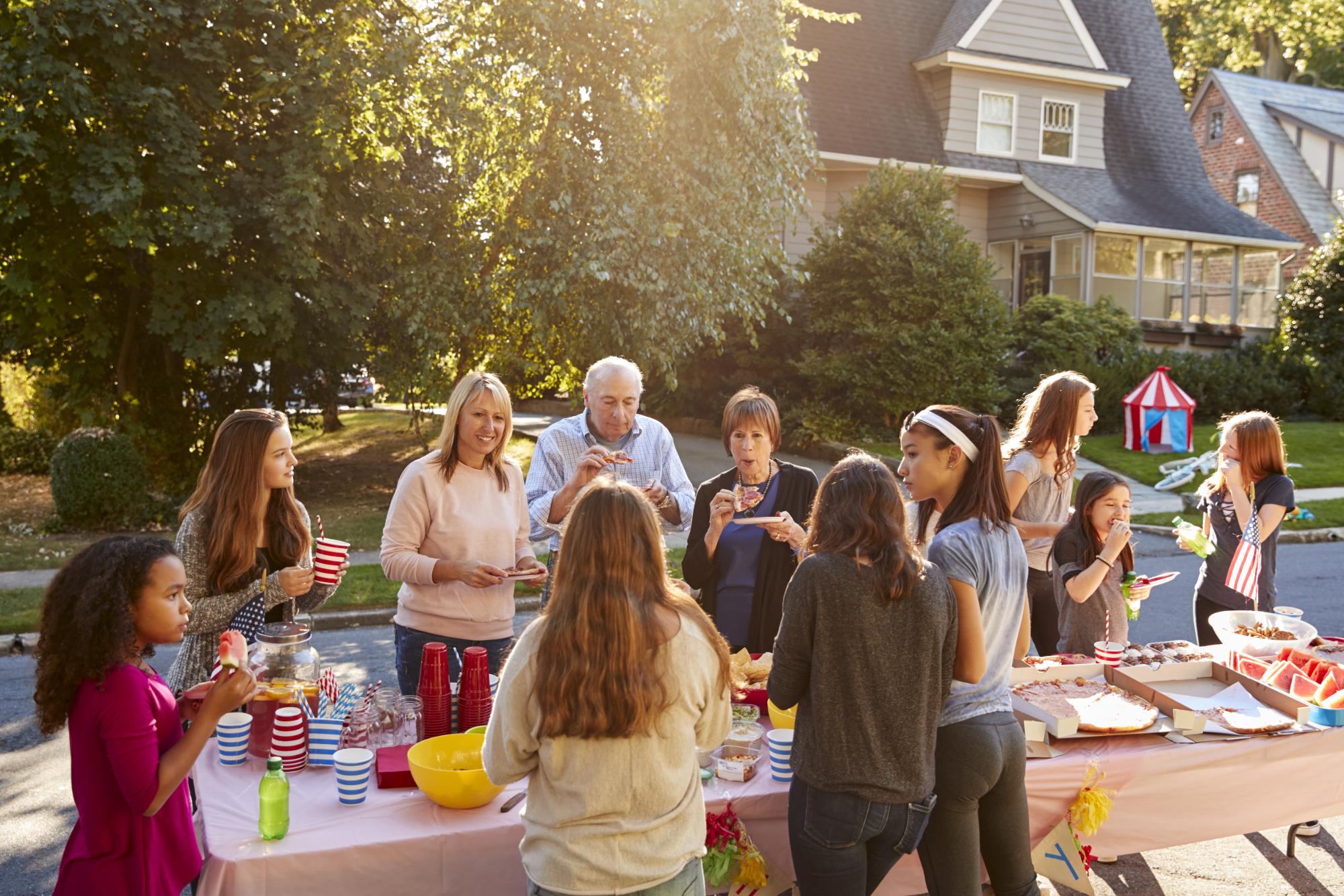 Neighbours talk and eat around a table at a block party