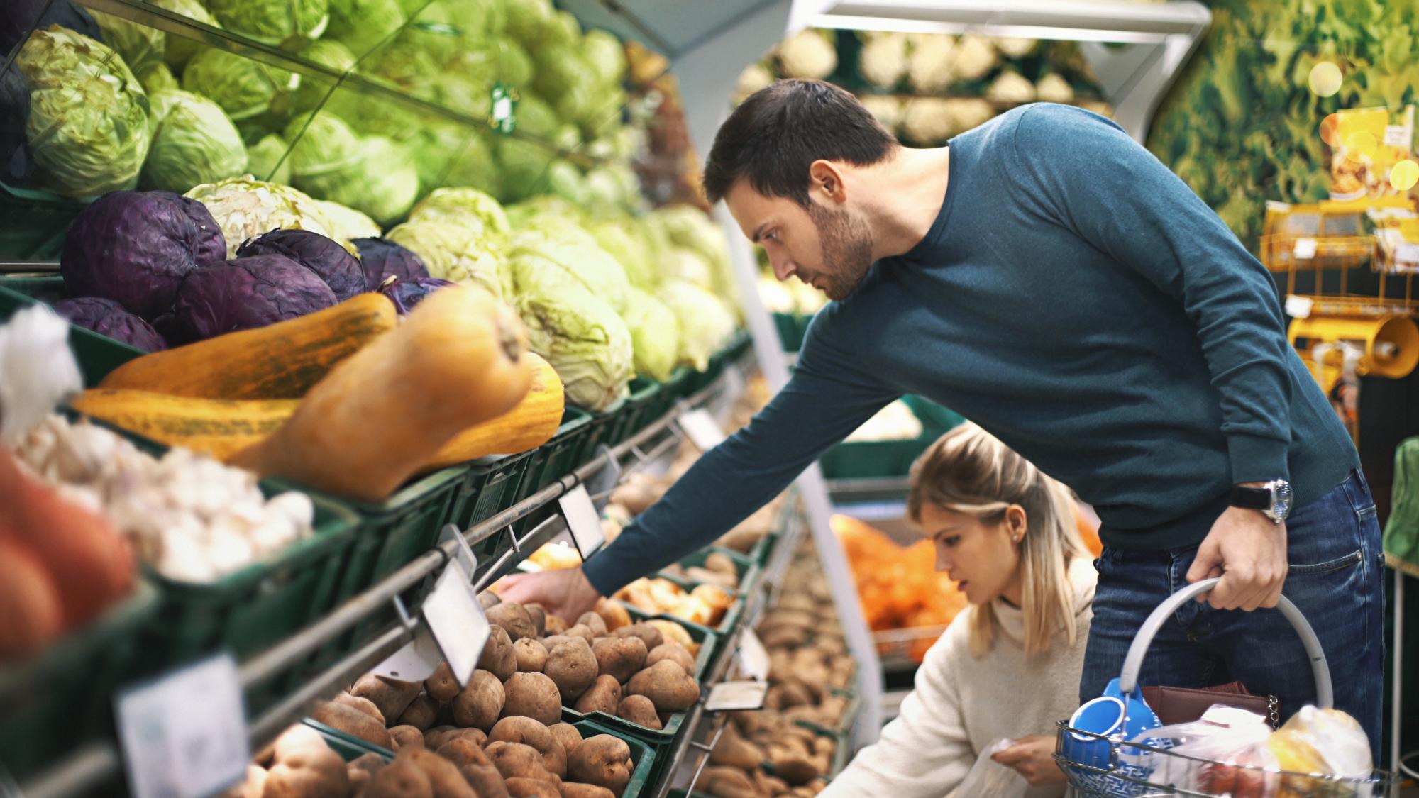 Couple in supermarket buying vegetables.