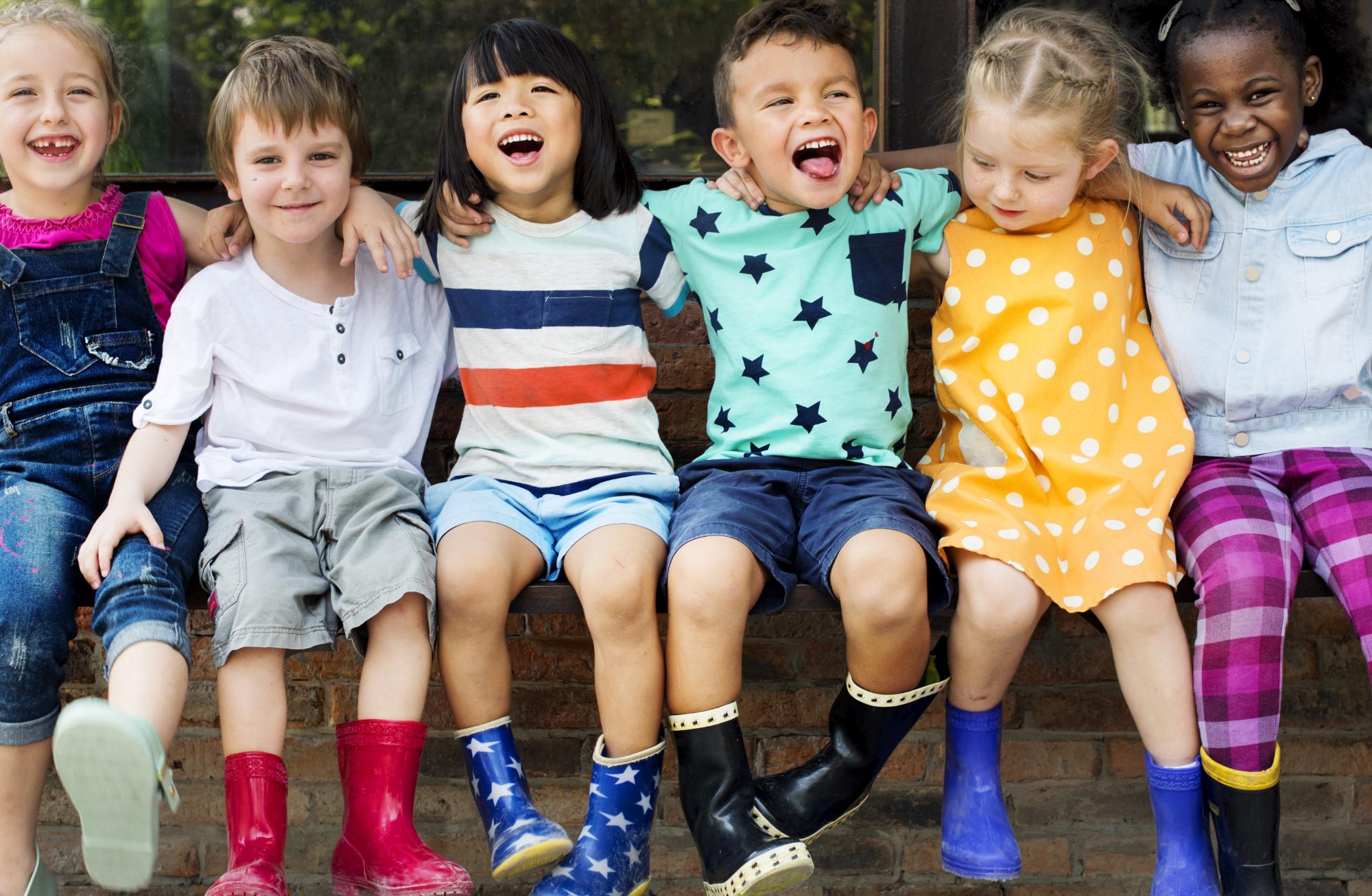 Group of kindergarten kids friends arm around sitting and smiling fun