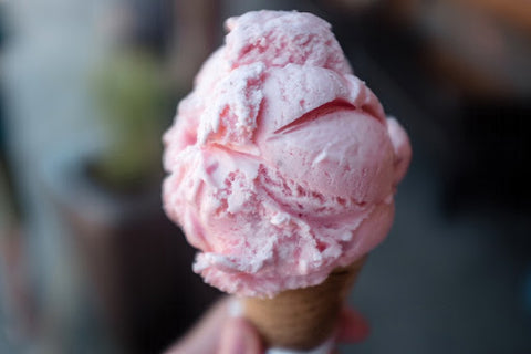 A scoop of strawberry ice cream in a cone