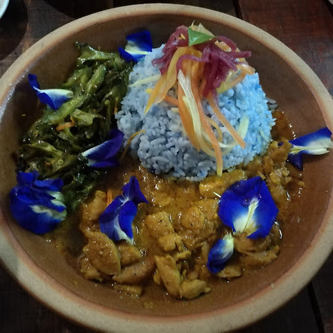 Asian bowl of food with blue pea infused rice, garnished with blue pea flowers