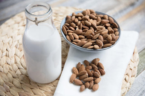 A glass of milk and a bowl of almonds next to it