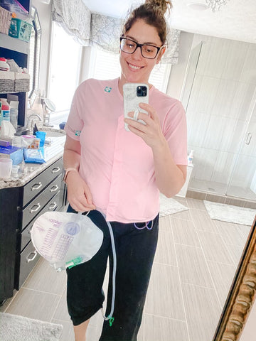 woman taking selfie standing holding foley catheter bag 