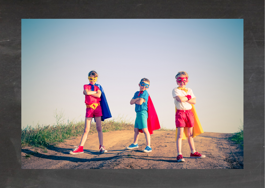 Kindergeburtstag Idee: Superheldenabenteuer. Drei Kinder stehen als Superhelden verkleidet auf einer Strasse.