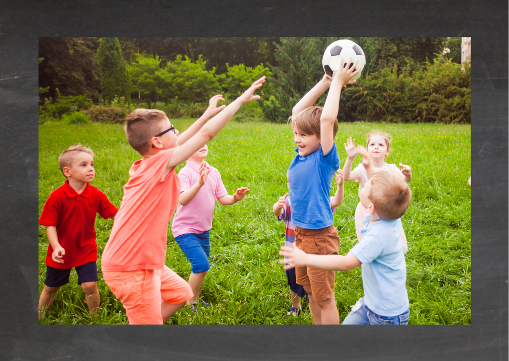Kindergeburtstag Idee: Olympiade. Kinder spielen auf der Wiese mit einem Ball.