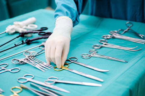 Detail shot of steralized surgery instruments with a hand grabbing a tool