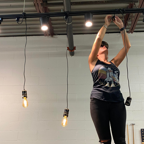 Anna Parker hanging lights in the coffee roastery