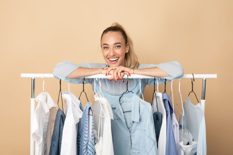 Young women smiles over capsule wardrobe on clothing rack