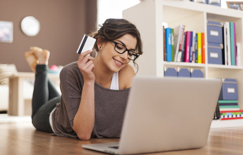 Woman with credit card in hand online shopping from laptop at home