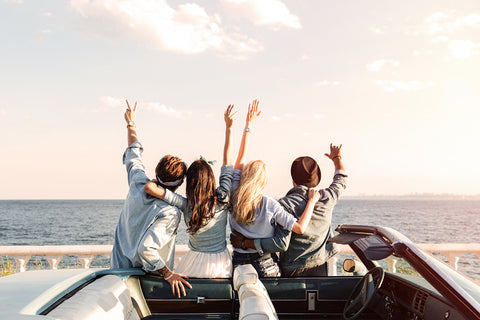 Friends on road trip taking picture in front of the ocean