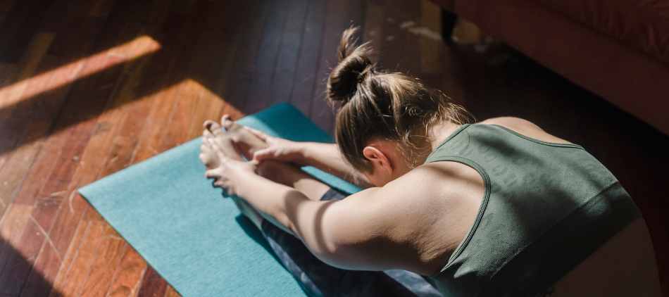 Person on yoga mat doing forward fold