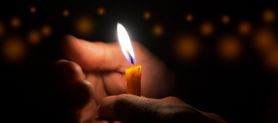 Photo of person shielding a lit candle