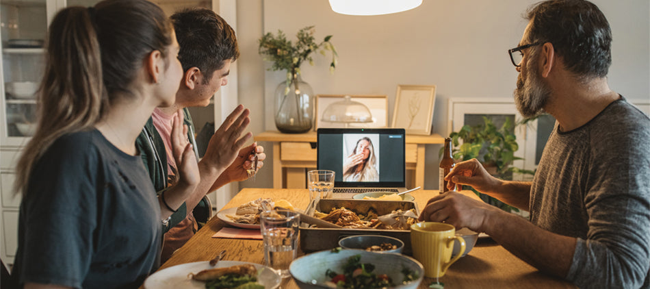 Father and Two Teenage Children at Dinner Table with Laptop on Table - Woman Joining Via Zoom