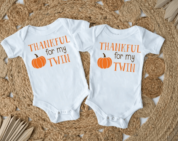 Matching white bodysuit outfits for twins. "Thankful for my twin" is printed on the front as well as a little pumpkin graphic