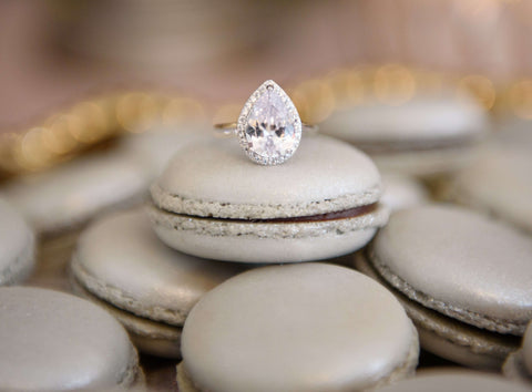 Pear shaped lab-grown diamond with diamond halo on some silver macarons