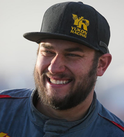 Headshot of Bailey Cole in race suit wearing a Team Yukon hat