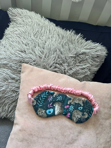 snow leopard sleepmask gift sat on a pillow 