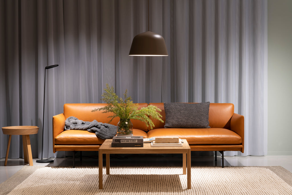 原色皮革沙發搭配木質邊桌及駝色地毯，則能使整體空間散發溫潤雅緻品味。