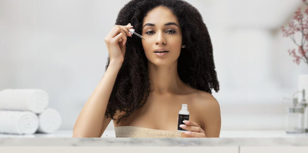 Multicultural woman applying IKNOW Cellular Retreat Plum Oil