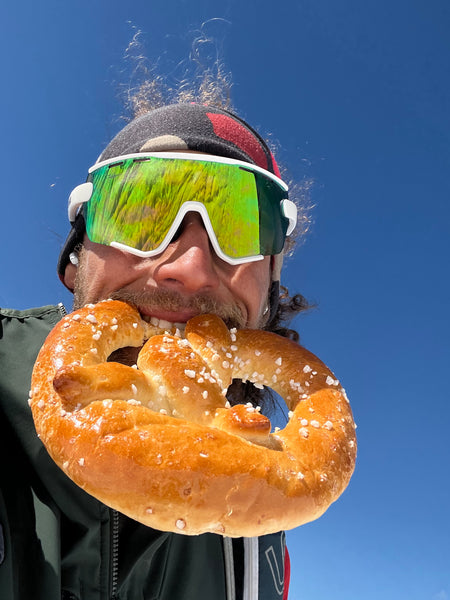 a man in uvex sunglasses eats a pretzel
