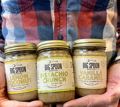 A person holds three jars of Big Spoon Roasters nut butter.