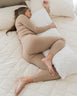 image of woman lying on her side with her top leg and arm supported by an organic wool body pillow