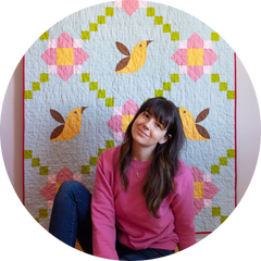 Gab sitting in front of a quilt with yellow birds