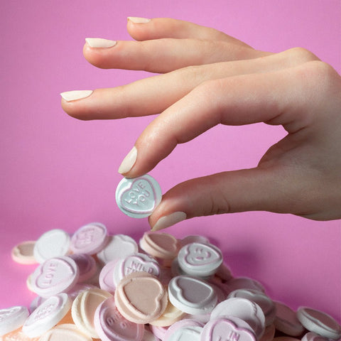 hand with pale cream manicure holding love heart saying love you