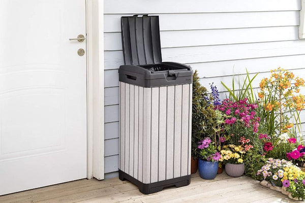 outdoor trash can sitting on a deck next to flowers