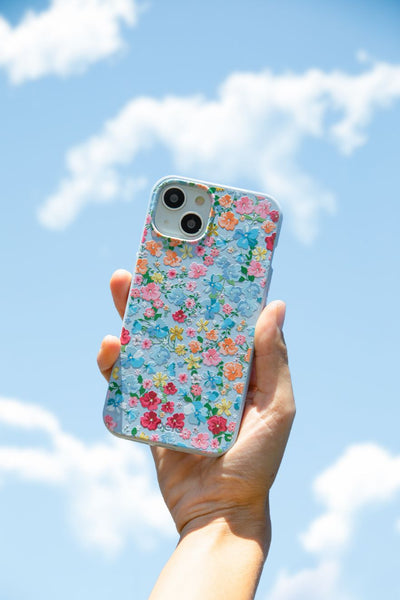 person holding a floral phone case up in front of a blue sky
